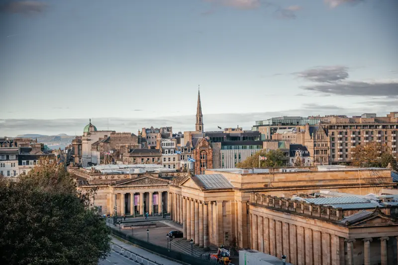 The neoclassical Scottish National Gallery with the Old Town skyline at golden hour